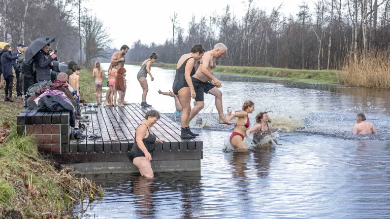 Klappertandende waaghalzen nemen nieuwjaarsduik in koude water Kanaal van Deurne